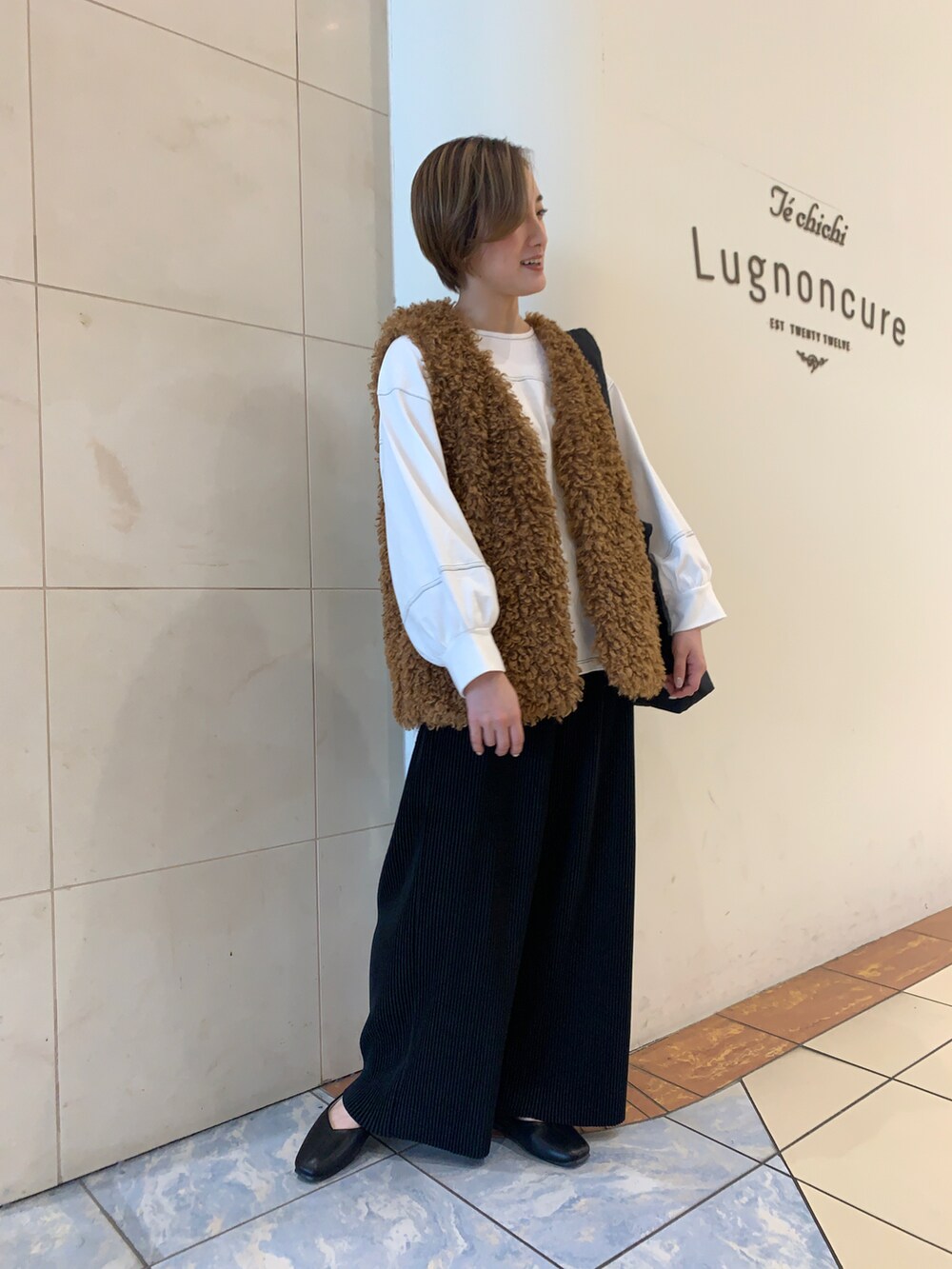 ホワイト系のTシャツ/カットソー、イエロー系のベスト、ブラック系のハンドバッグを着用したレディースの秋コーディネートの3枚目の写真