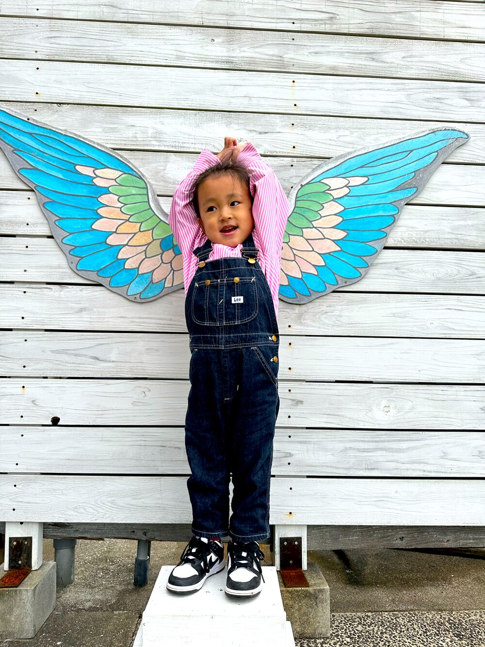 ピンク系のシャツ/ブラウス、ブルー系のサロペット/オーバーオール、ホワイト系のスニーカーを着用したキッズの春コーディネートの2枚目の写真