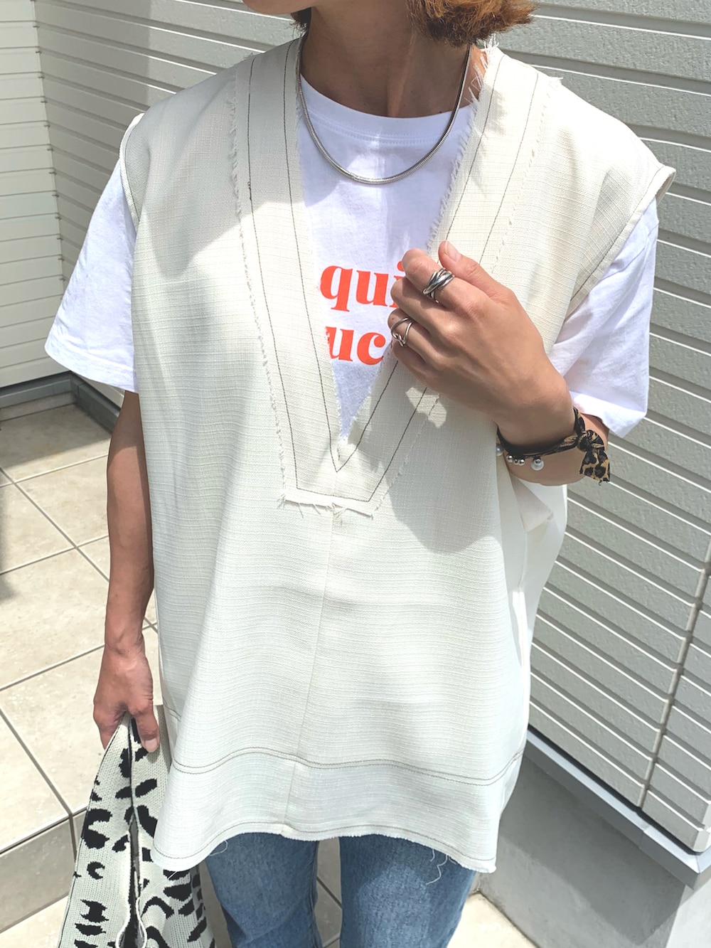 ホワイト系のベスト、ブラック系のサンダル、ベージュ系のキャップを着用したレディースの夏コーディネートの2枚目の写真