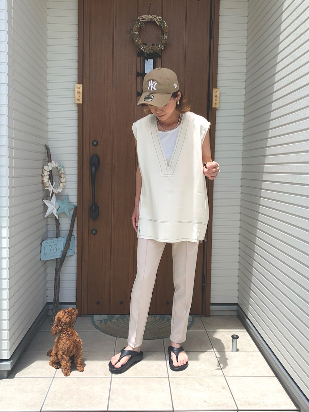 ホワイト系のベスト、ブラック系のサンダル、ベージュ系のキャップを着用したレディースの夏コーディネートの4枚目の写真