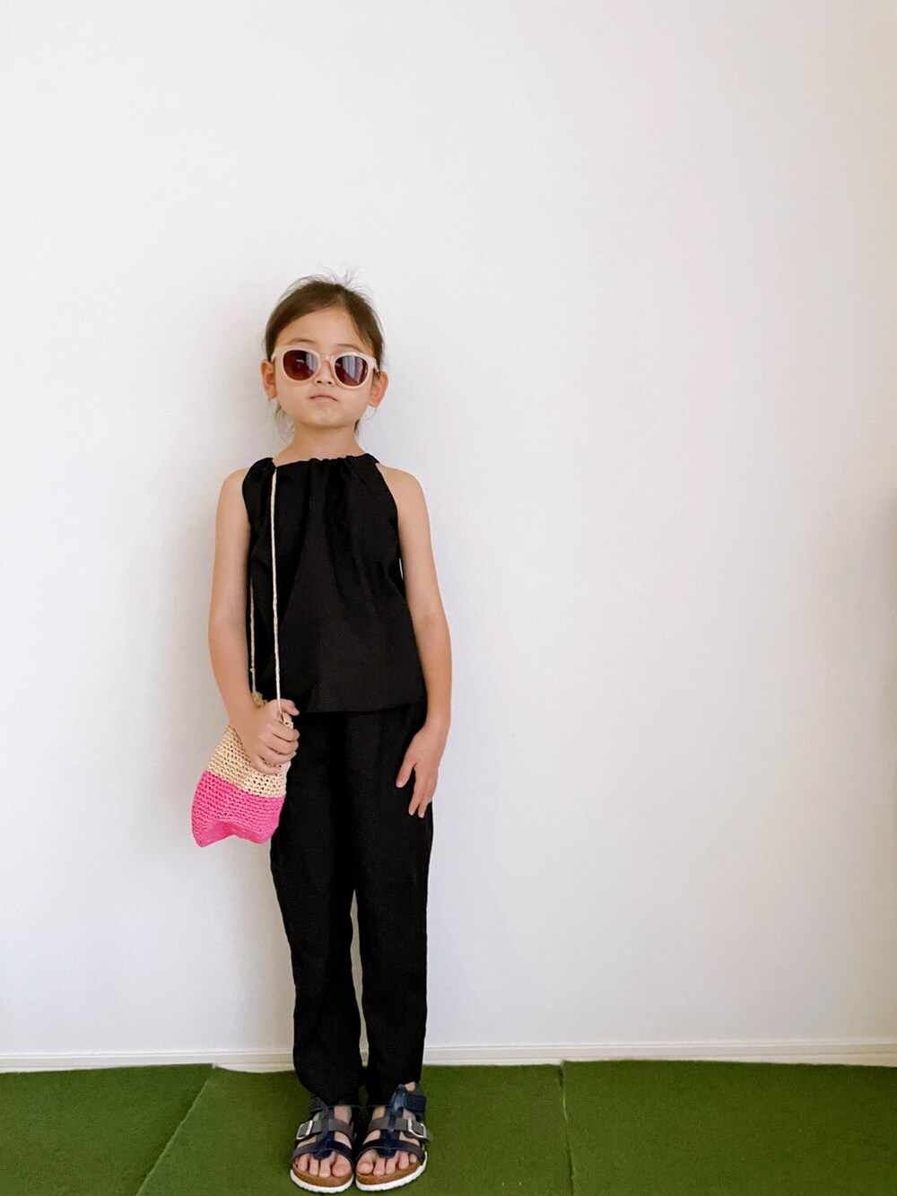 ブラック系のキャミソール、ブラック系のその他パンツ、ピンク系のかごバッグを着用したキッズの夏コーディネートの3枚目の写真