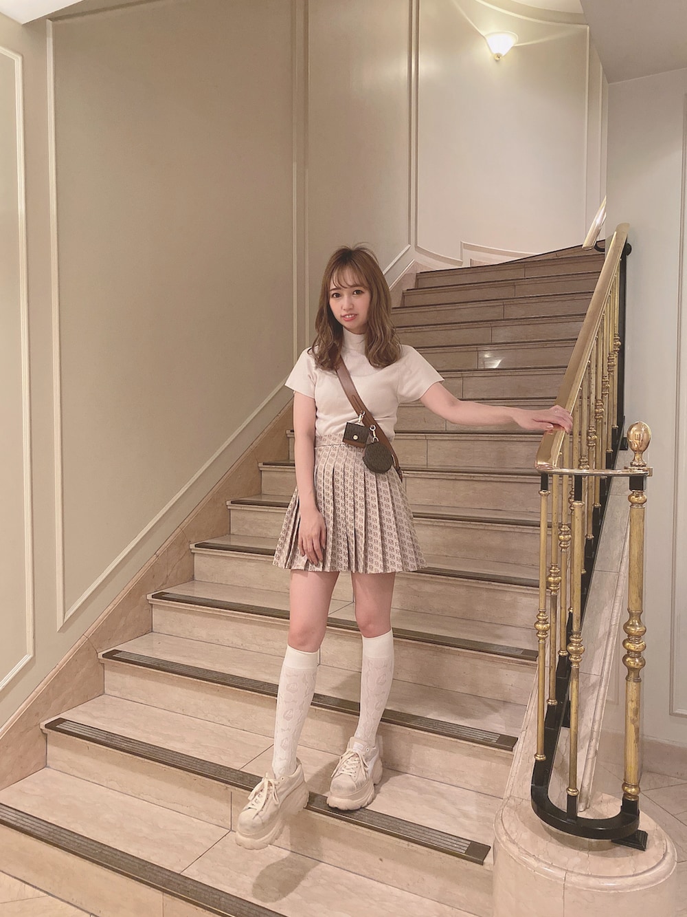 ブラウン系のスカート、ブラウン系のショルダーバッグ、ベージュ系のスニーカーを着用したレディースの夏コーディネートの4枚目の写真