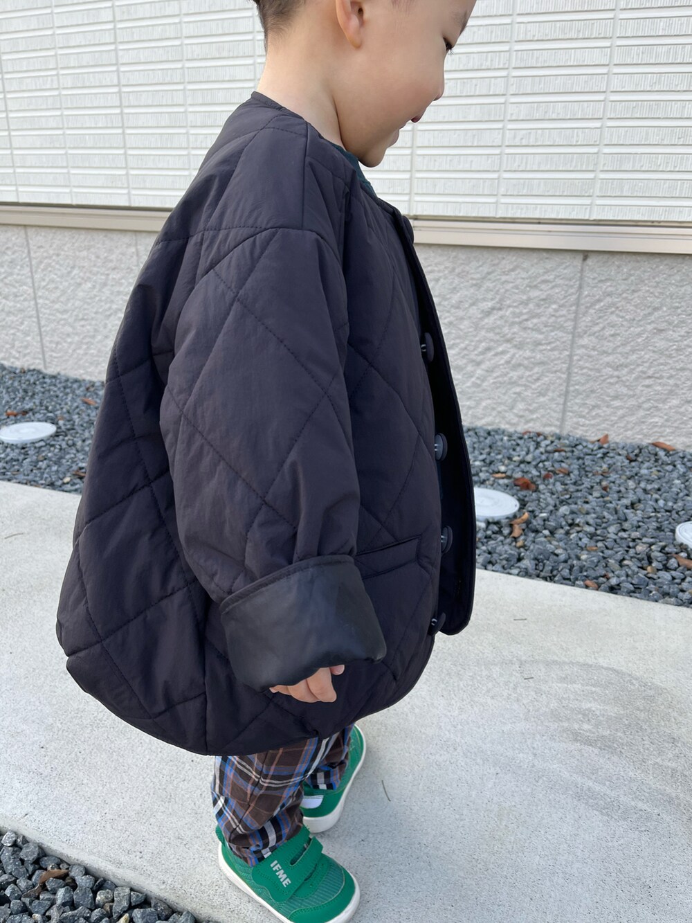 ブラック系のブルゾン、グリーン系のTシャツ/カットソー、ブラウン系のパンツを着用したキッズの秋コーディネートの3枚目の写真
