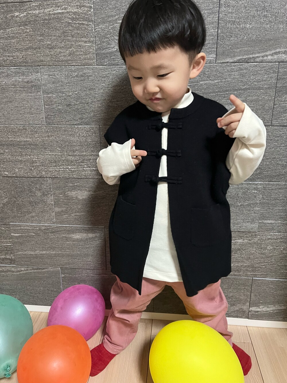 ブラック系のベスト、ホワイト系のトップス、ピンク系のチノパンツを着用したキッズの冬コーディネートの2枚目の写真