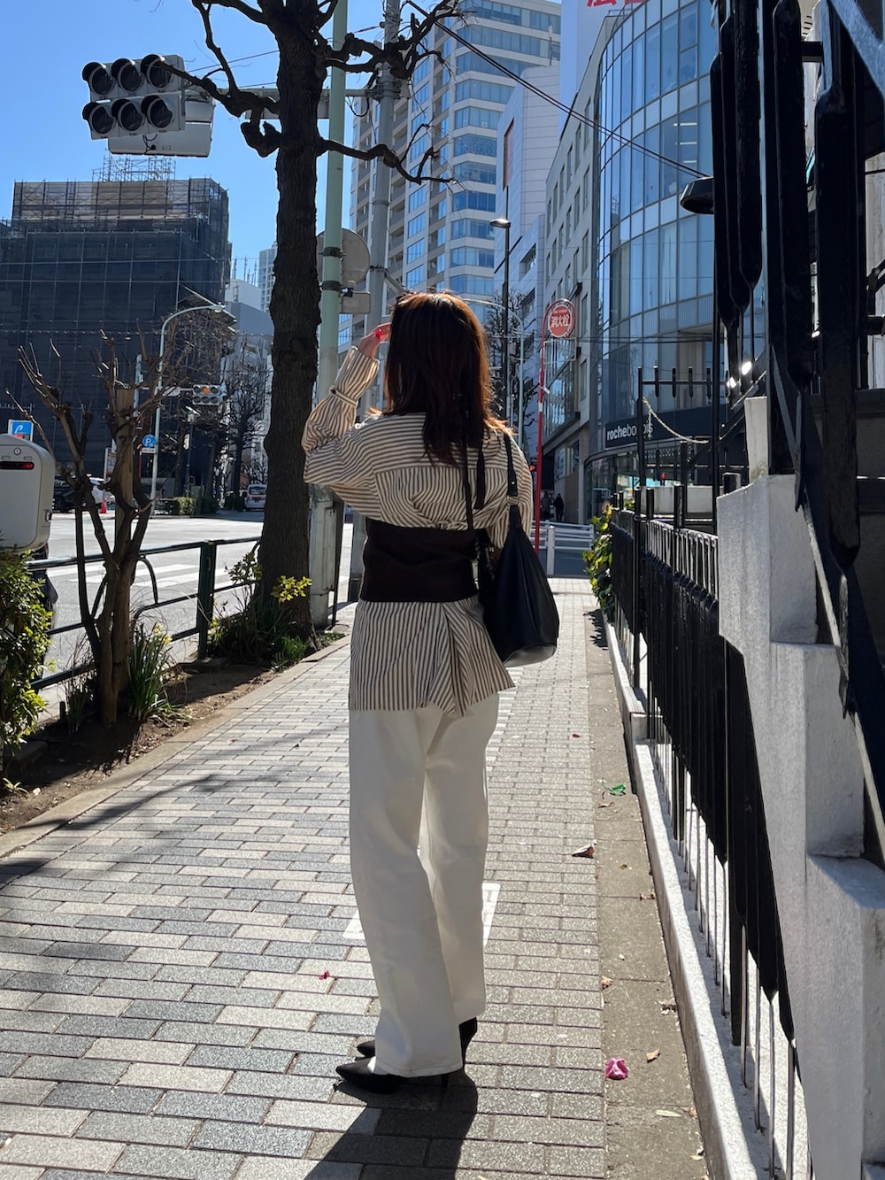 ブラウン系のシャツ/ブラウス、ブラウン系のニット/セーター、ホワイト系のデニムパンツを着用したレディースの冬コーディネートの5枚目の写真