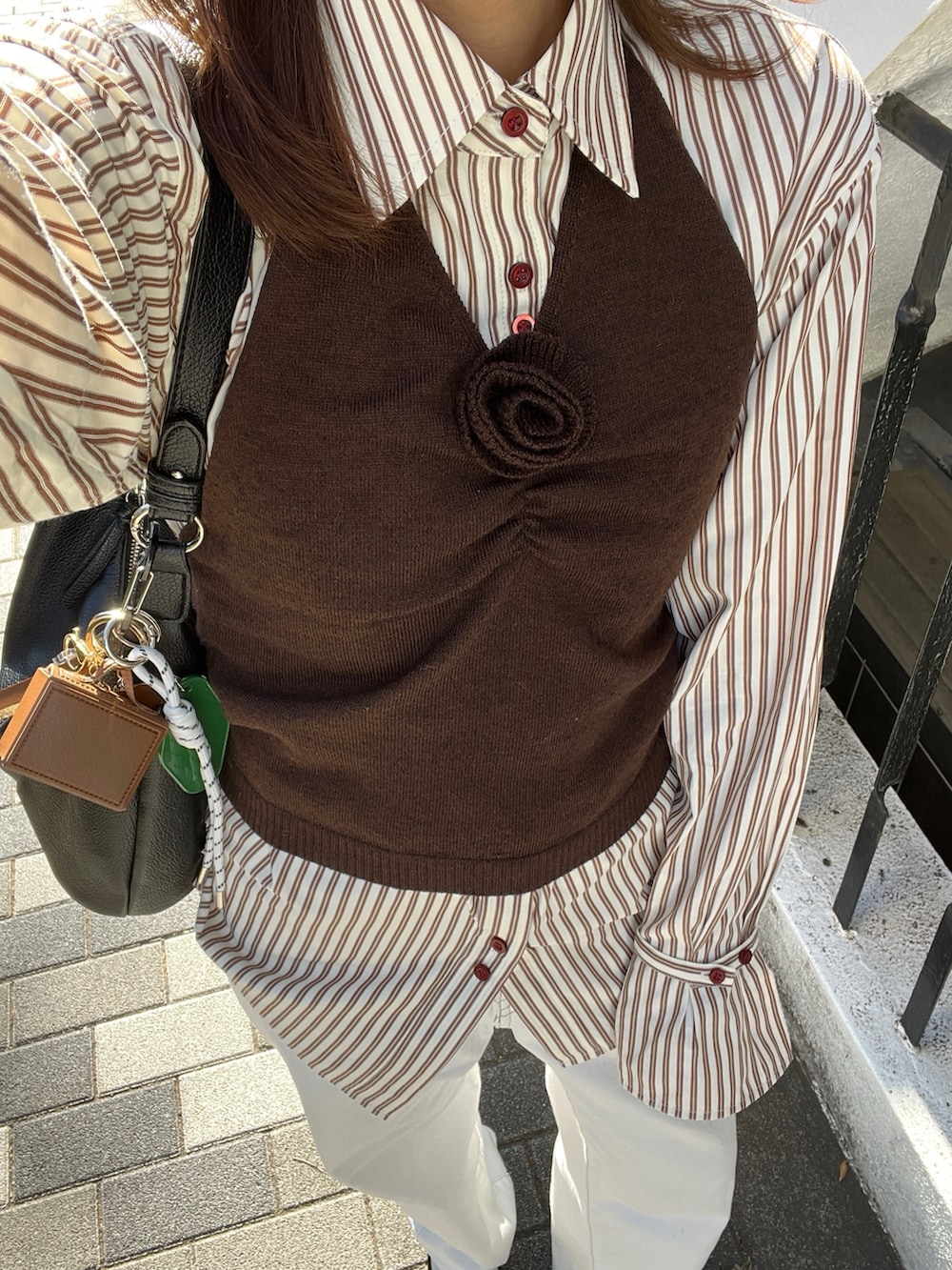ブラウン系のシャツ/ブラウス、ブラウン系のニット/セーター、ホワイト系のデニムパンツを着用したレディースの冬コーディネートの6枚目の写真