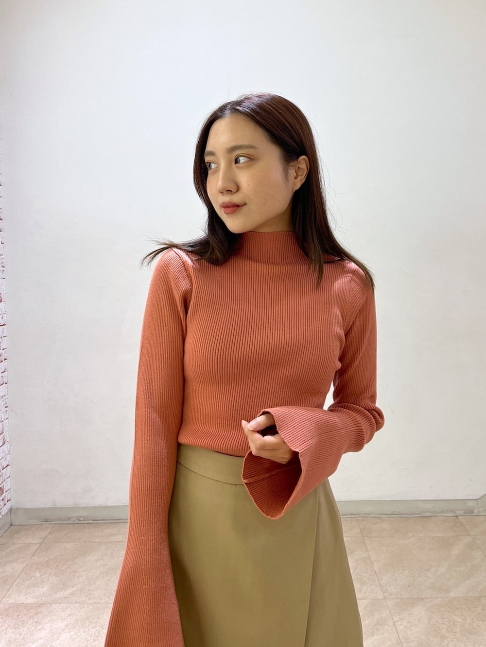 オレンジ系のニット/セーター、ベージュ系のその他パンツを着用したレディースの秋コーディネートの4枚目の写真