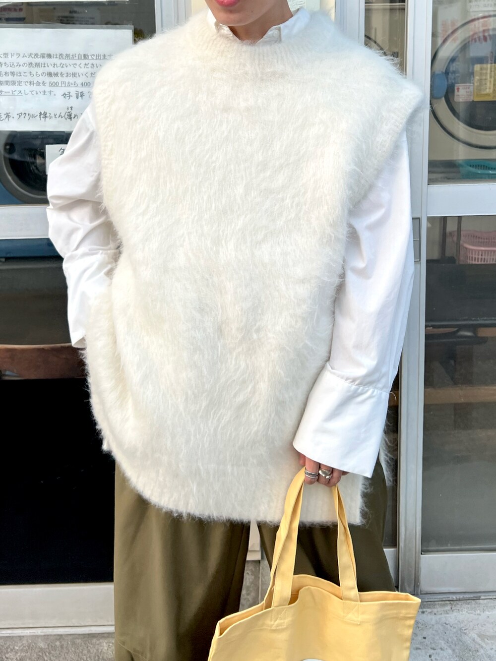 グリーン系のパンツ、ホワイト系のニット/セーター、イエロー系のトートバッグを着用したメンズの秋コーディネートの3枚目の写真