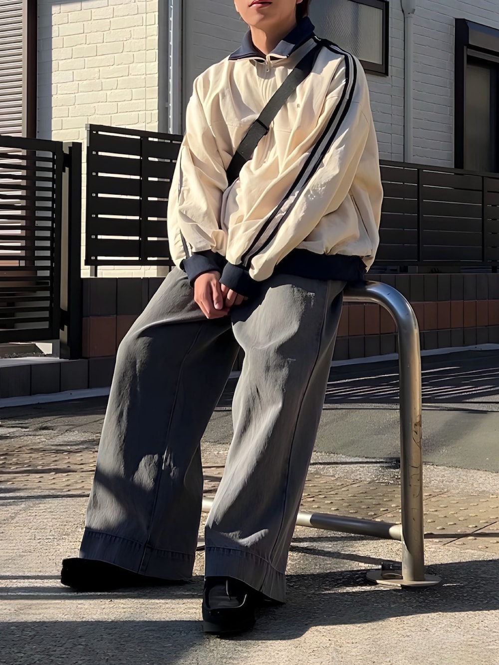 グレー系のデニムパンツ、ブラック系のスニーカー、ベージュ系のトップスを着用したメンズの冬コーディネートの2枚目の写真