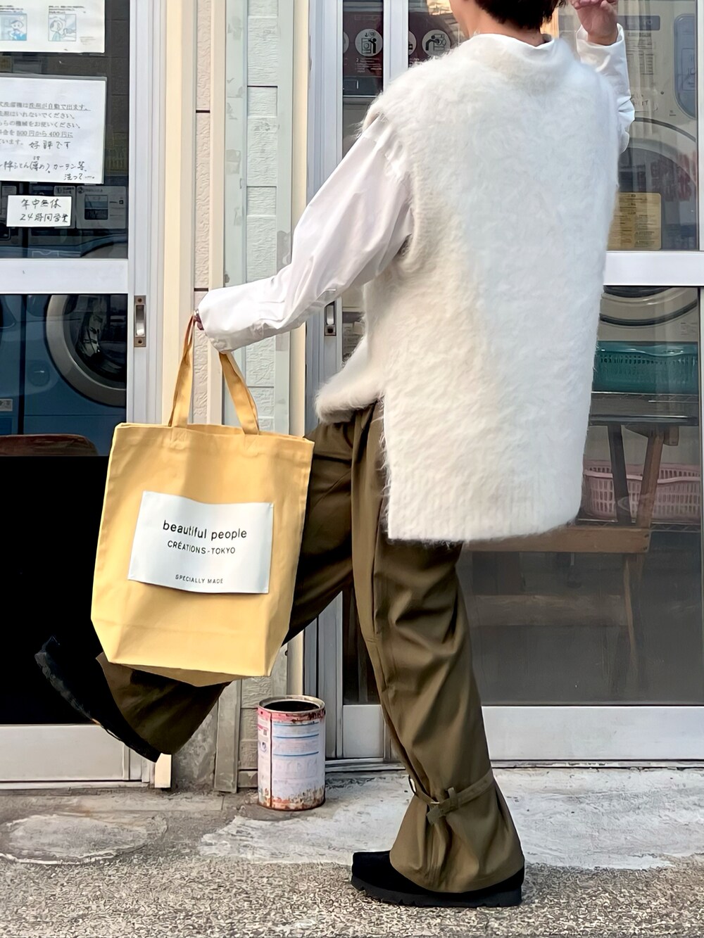 グリーン系のパンツ、ホワイト系のニット/セーター、イエロー系のトートバッグを着用したメンズの秋コーディネートの2枚目の写真