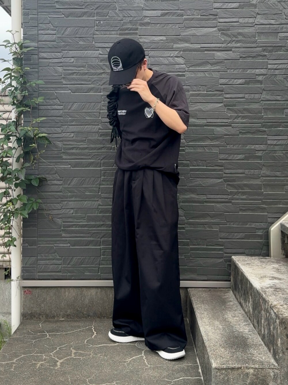 ブラック系のTシャツ/カットソー、ブラック系のスラックス、ブラック系のスニーカーを着用したメンズの夏コーディネートの2枚目の写真