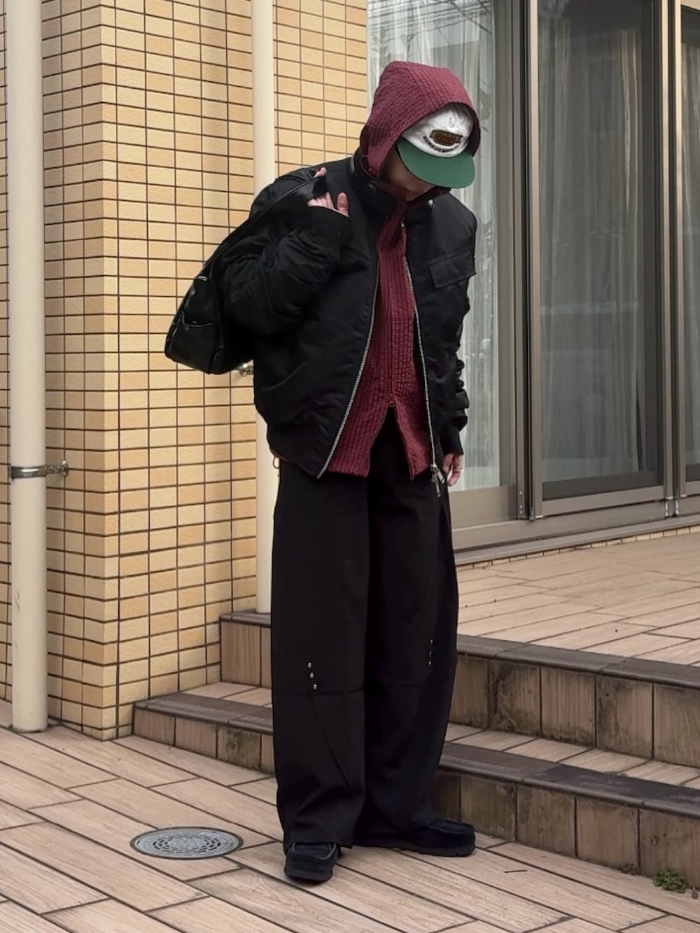 ブラック系のナイロンジャケット、レッド系のブルゾン、ブラック系のスラックスを着用したメンズの秋コーディネートの2枚目の写真