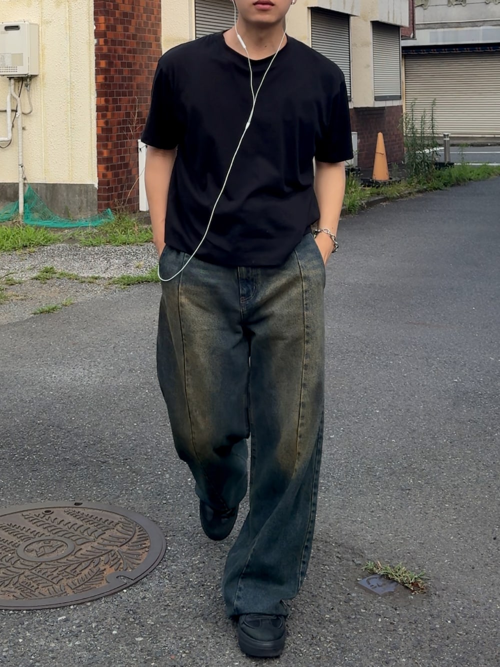 ブルー系のデニムパンツ、ブラック系のTシャツ/カットソー、ブラック系のシューズを着用したメンズの夏コーディネートの2枚目の写真