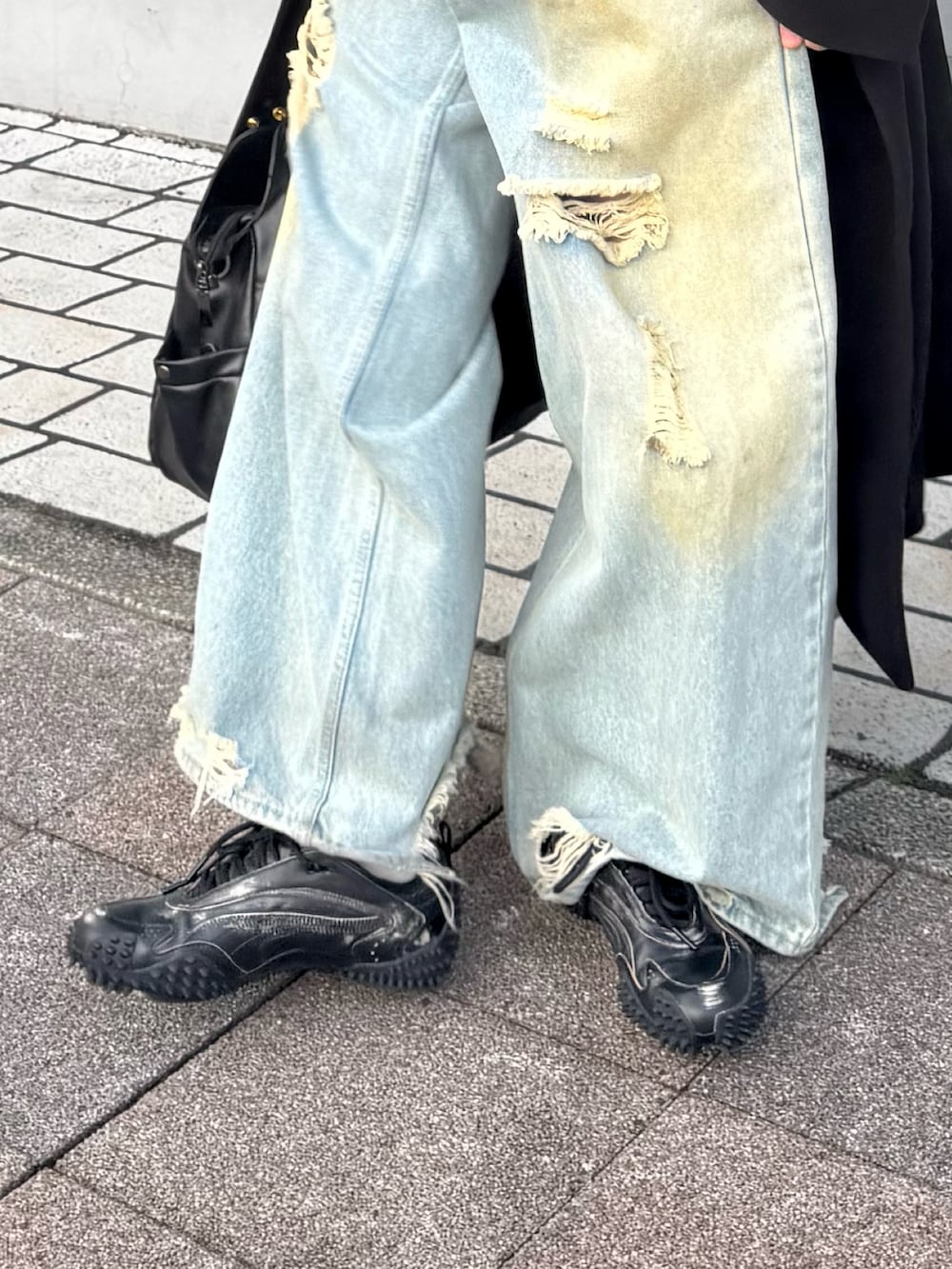 ブラック系のニット/セーター、ブルー系のデニムパンツ、ブラック系のステンカラーコートを着用したメンズの冬コーディネートの3枚目の写真