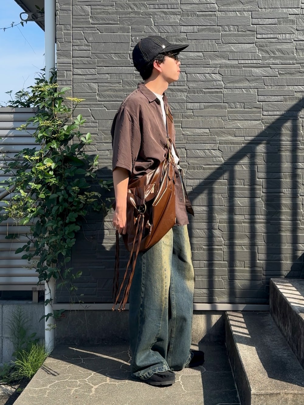 ブラウン系のシャツ/ブラウス、ブルー系のデニムパンツ、ブラック系のスニーカーを着用したメンズの夏コーディネートの2枚目の写真