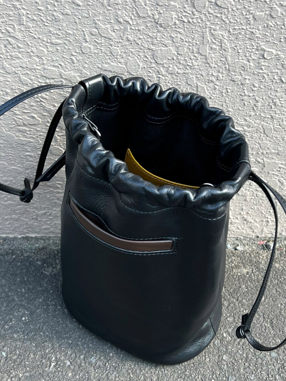 ブラック系のハンドバッグ、ブルー系のデニムパンツ、ブラック系のローファーを着用したメンズの秋コーディネートの4枚目の写真