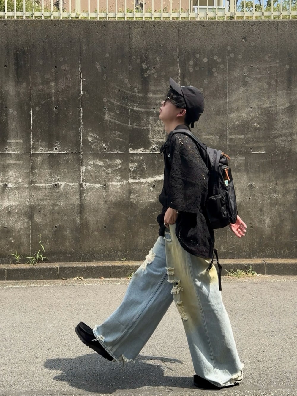 ブラック系のポロシャツ、ブラック系のバックパック/リュック、ブルー系のデニムパンツを着用したメンズの秋コーディネートの2枚目の写真