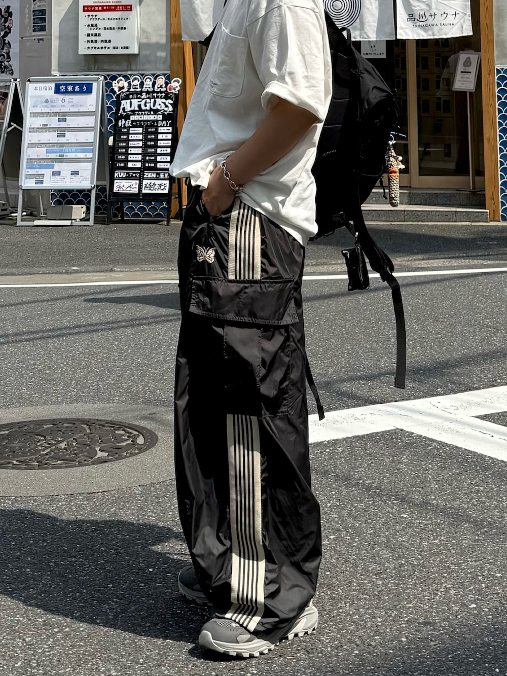ホワイト系のTシャツ/カットソー、ブラック系のバックパック/リュック、グレー系のスニーカーを着用したメンズの夏コーディネートの2枚目の写真
