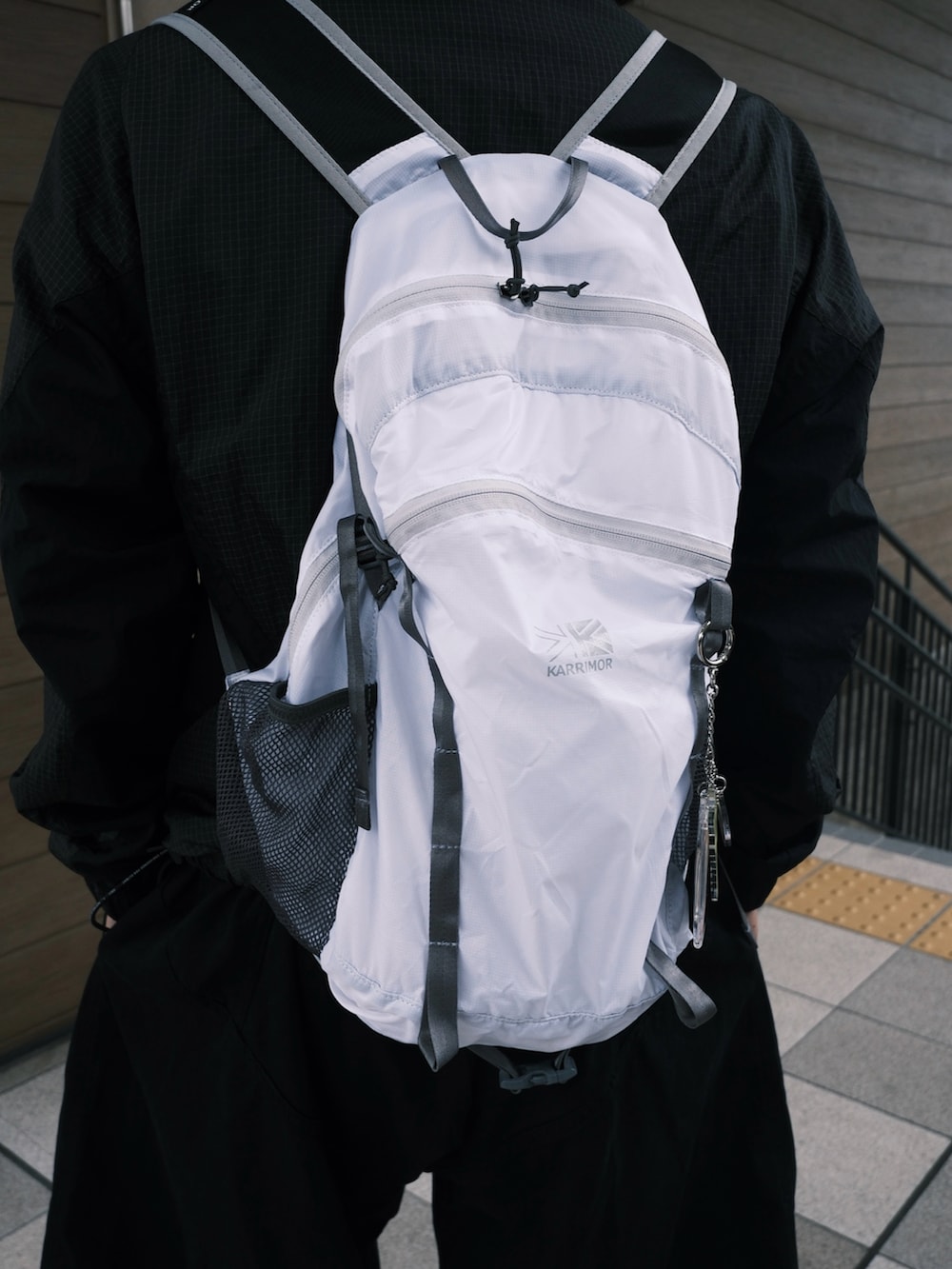 ブルー系のスニーカー、ホワイト系のバックパック/リュック、ブラック系のその他パンツを着用したメンズの秋コーディネートの3枚目の写真