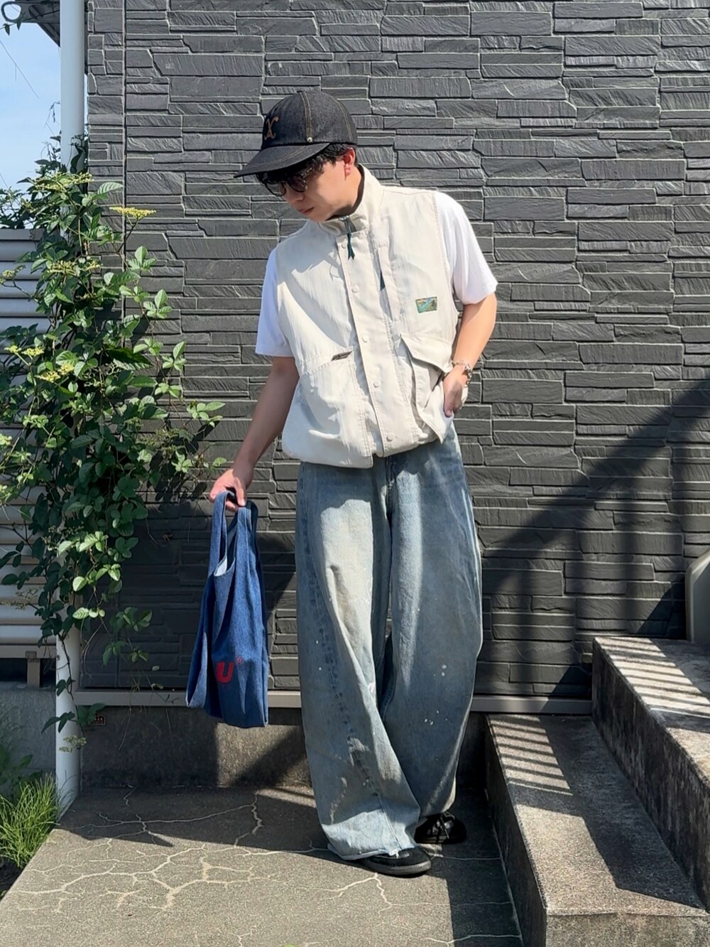 ブルー系のデニムパンツ、ブラック系のスニーカー、ブルー系のショルダーバッグを着用したメンズの夏コーディネートの2枚目の写真