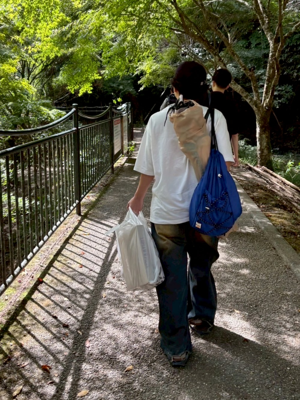 ブルー系のバックパック/リュック、ホワイト系のTシャツ/カットソー、グリーン系のサンダルを着用したメンズの秋コーディネートの2枚目の写真