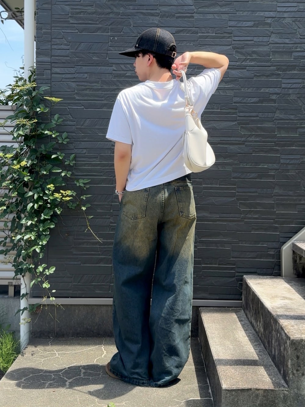 ブルー系のデニムパンツ、ホワイト系のTシャツ/カットソー、ブラウン系のスニーカーを着用したメンズの夏コーディネートの2枚目の写真