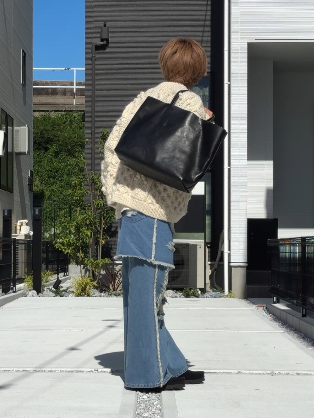 ブルー系のデニムパンツ、ホワイト系のニット/セーター、ブラック系のトートバッグを着用したメンズの秋コーディネートの2枚目の写真