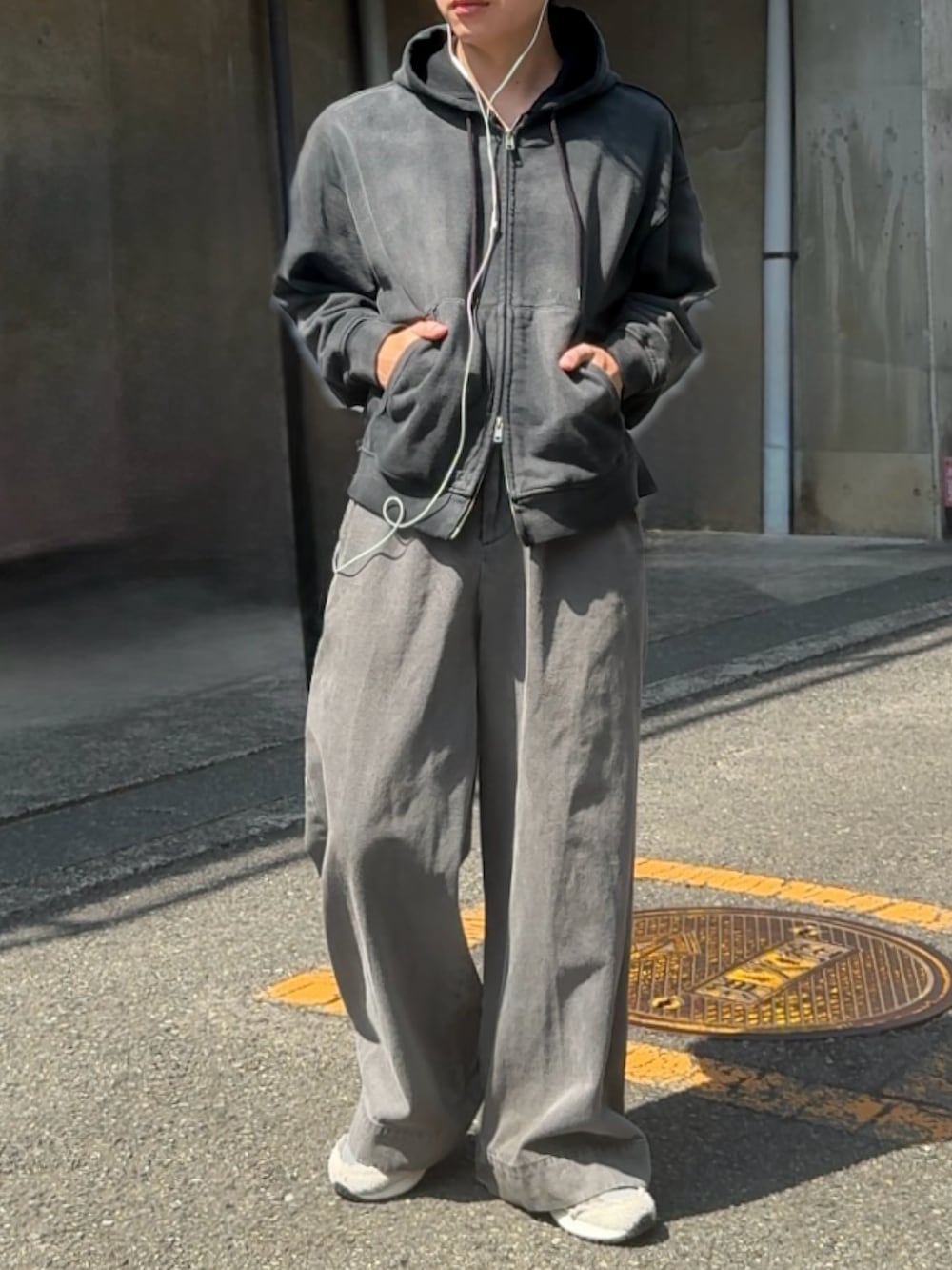 グレー系のスニーカー、ブラック系のパーカー、グレー系のデニムパンツを着用したメンズの秋コーディネートの2枚目の写真