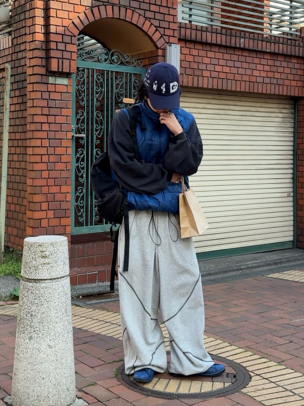 グレー系のスウェットパンツ、ブルー系のスウェット、ブルー系のダウンベストを着用したメンズの春コーディネートの3枚目の写真