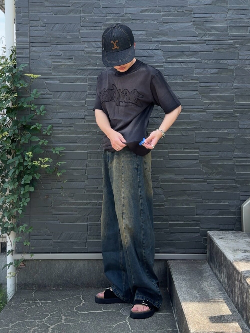 ブラック系のTシャツ/カットソー、ブルー系のデニムパンツ、ホワイト系のサンダルを着用したメンズの夏コーディネートの2枚目の写真