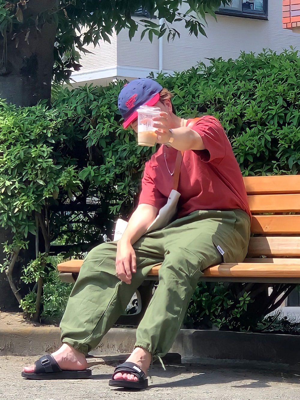 レッド系のTシャツ/カットソー、グリーン系のカーゴパンツ、ブラック系のサンダルを着用したメンズの夏コーディネートの2枚目の写真