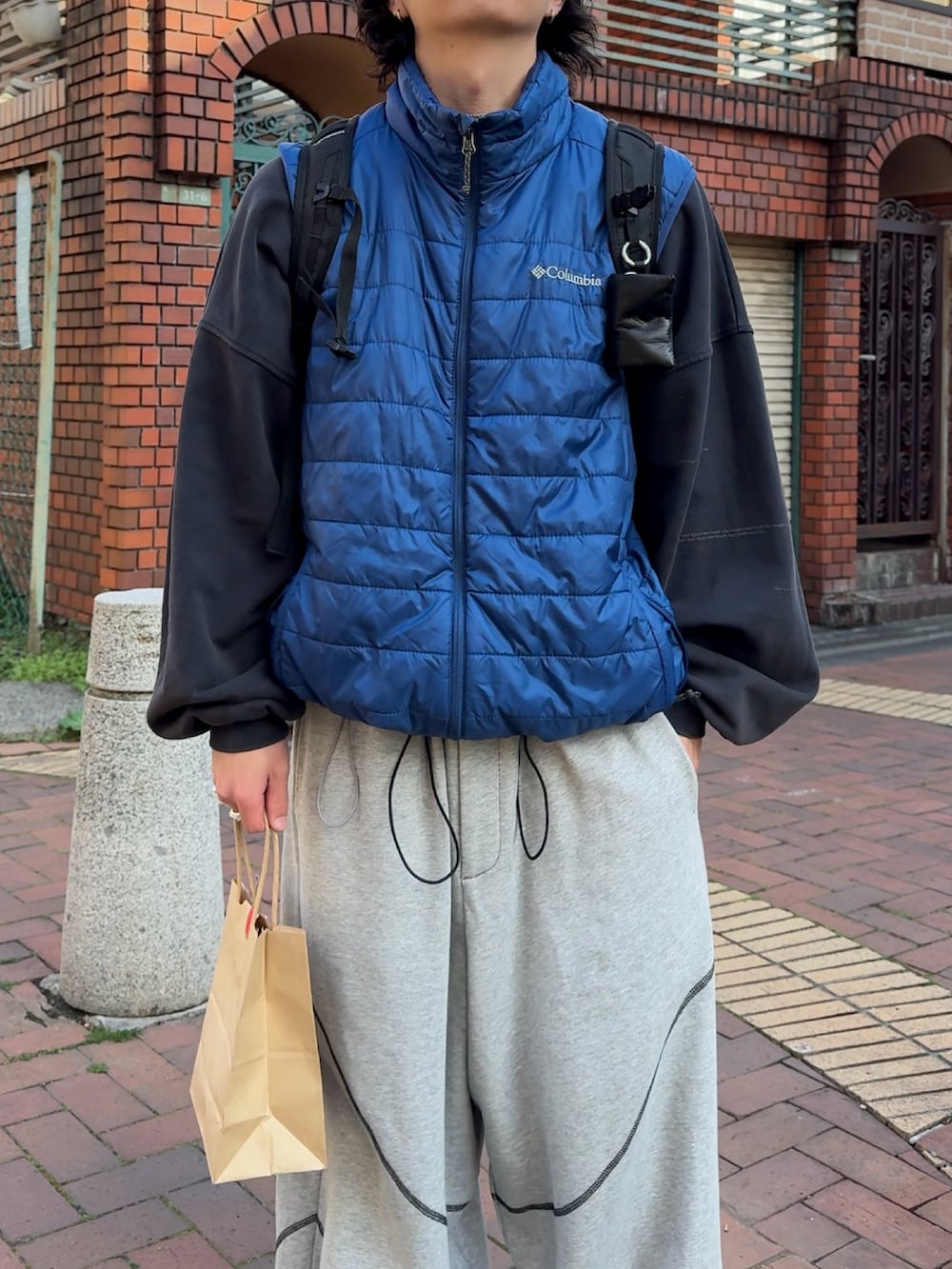 グレー系のスウェットパンツ、ブルー系のスウェット、ブルー系のダウンベストを着用したメンズの春コーディネートの2枚目の写真