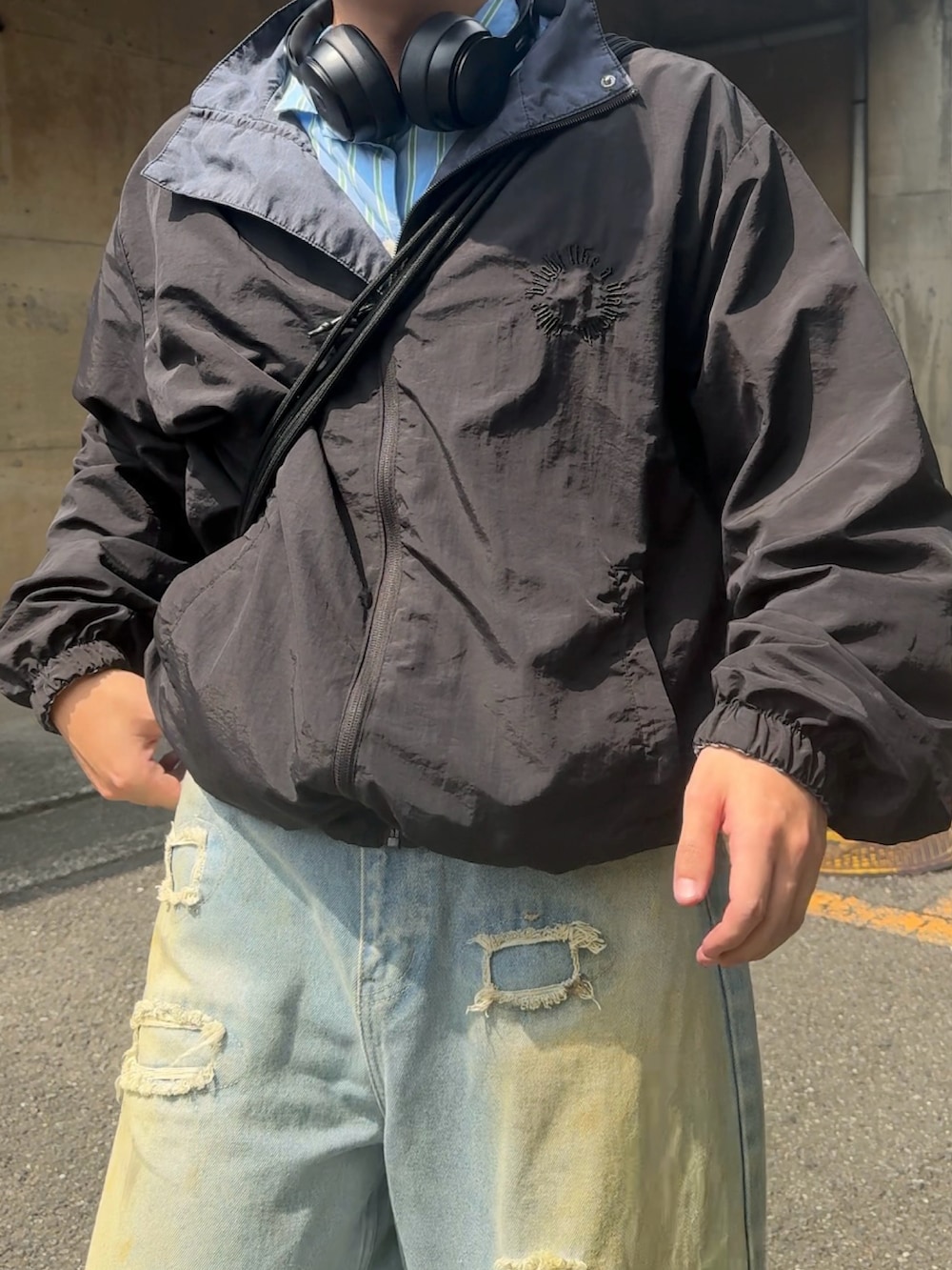 ブルー系のデニムパンツ、ベージュ系のブルゾン、ブラック系のスニーカーを着用したメンズの秋コーディネートの3枚目の写真