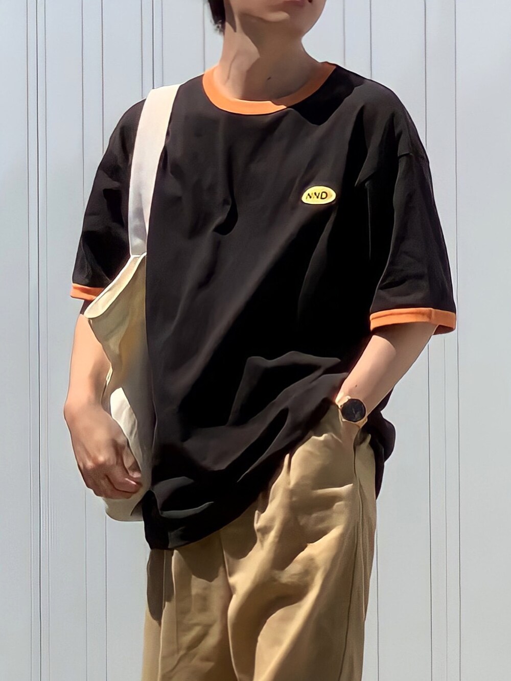 ベージュ系のチノパンツ、ブラウン系のTシャツ/カットソー、ホワイト系のトートバッグを着用したメンズの夏コーディネートの3枚目の写真