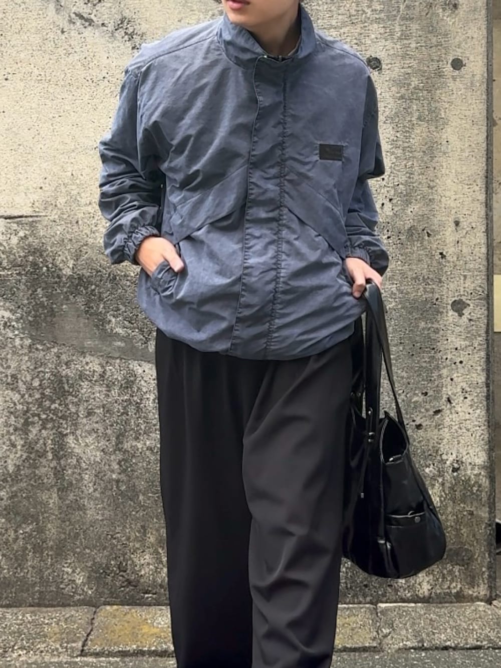 ブラック系のショルダーバッグ、ブラック系のスラックス、ベージュ系のブルゾンを着用したメンズの秋コーディネートの3枚目の写真