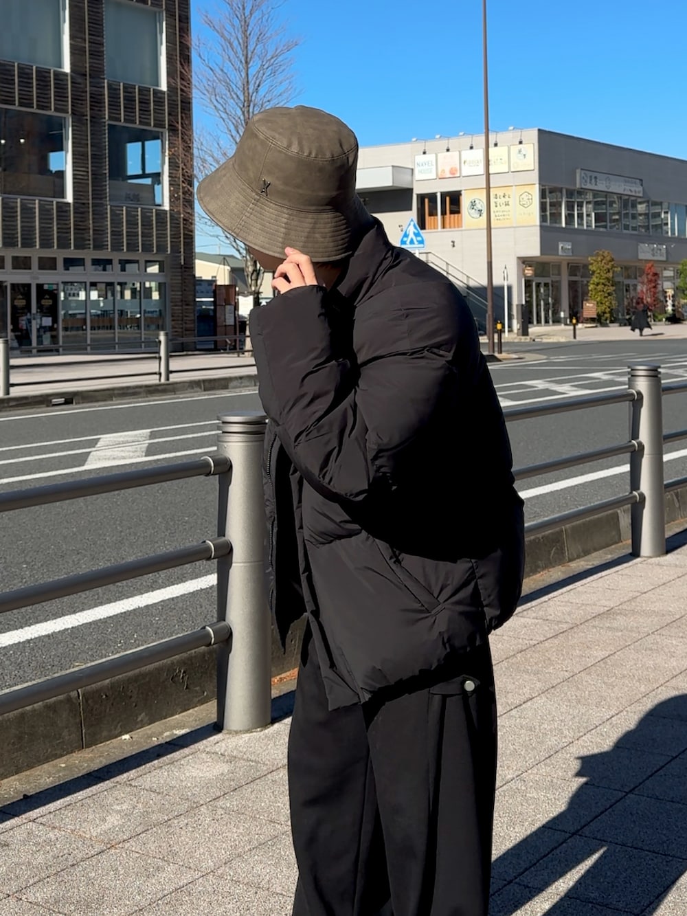 ブラック系のダウンジャケット/コート、ホワイト系のニット/セーター、ブラック系のスウェットパンツを着用したメンズの冬コーディネートの2枚目の写真