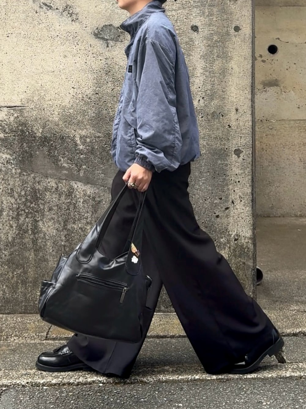 ブラック系のショルダーバッグ、ブラック系のスラックス、ベージュ系のブルゾンを着用したメンズの秋コーディネートの2枚目の写真