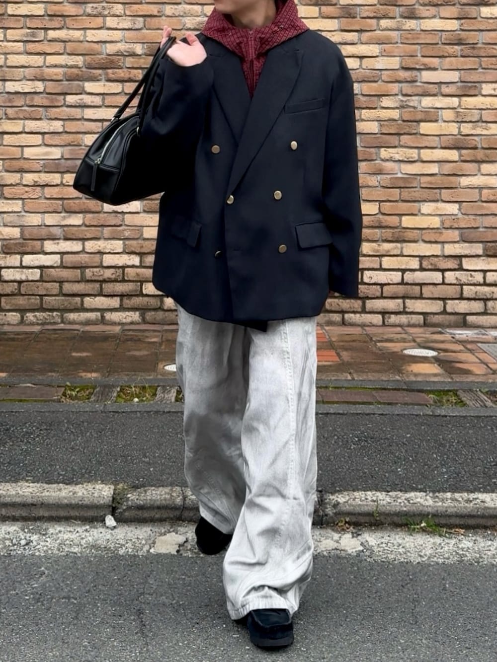 レッド系のブルゾン、ブルー系のテーラードジャケット、レッド系のボストンバッグを着用したメンズの秋コーディネートの3枚目の写真