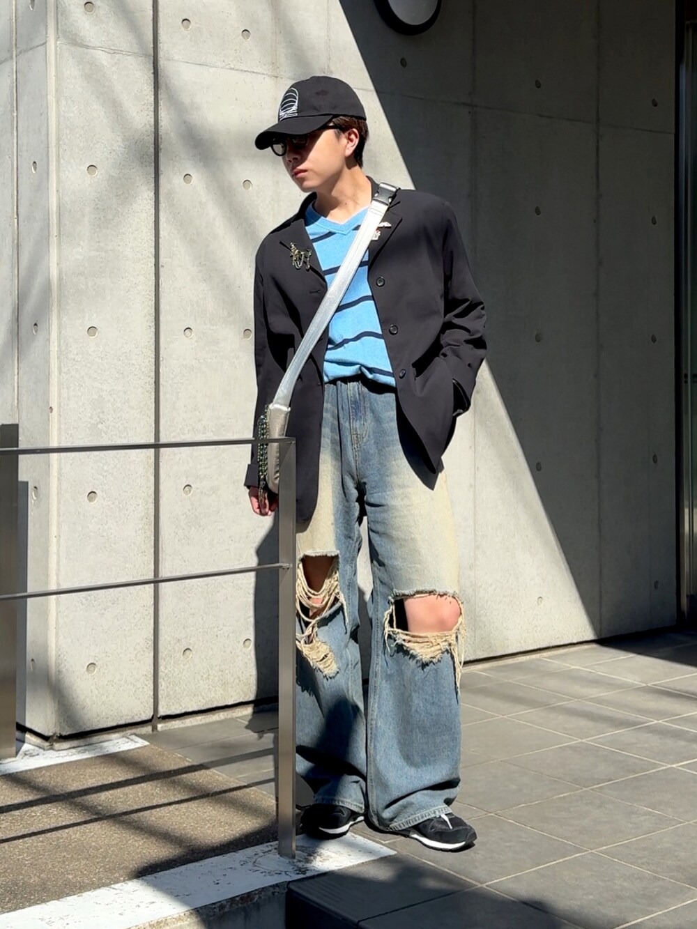 ブラック系のスニーカー、ブルー系のデニムパンツ、シルバー系のバッグを着用したメンズの春コーディネートの2枚目の写真