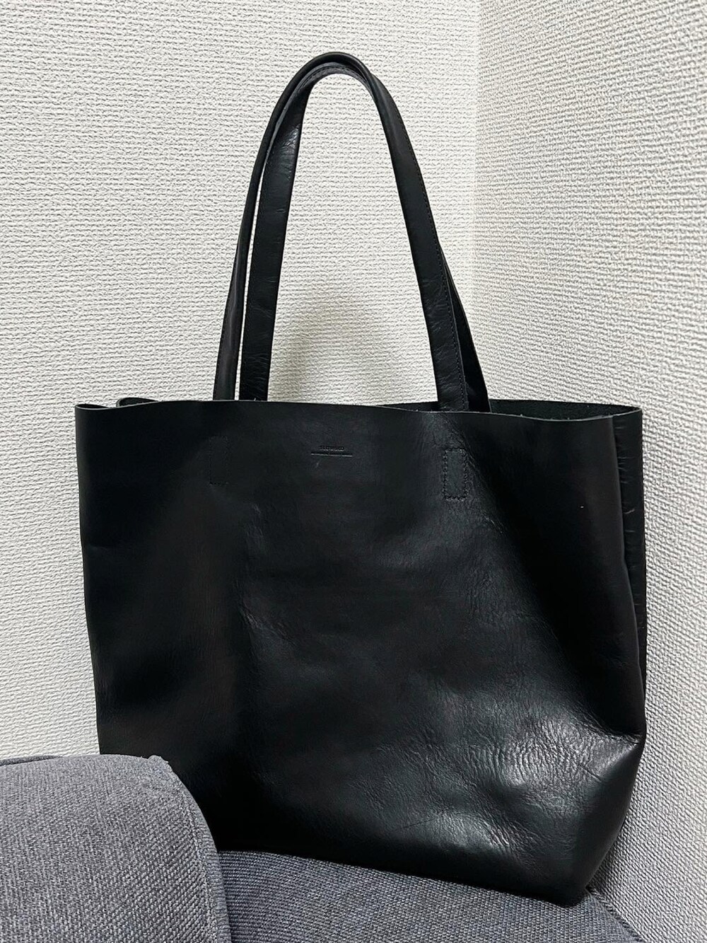 ブラック系のベスト、ホワイト系のチノパンツ、ブラック系のローファーを着用したメンズの秋コーディネートの2枚目の写真