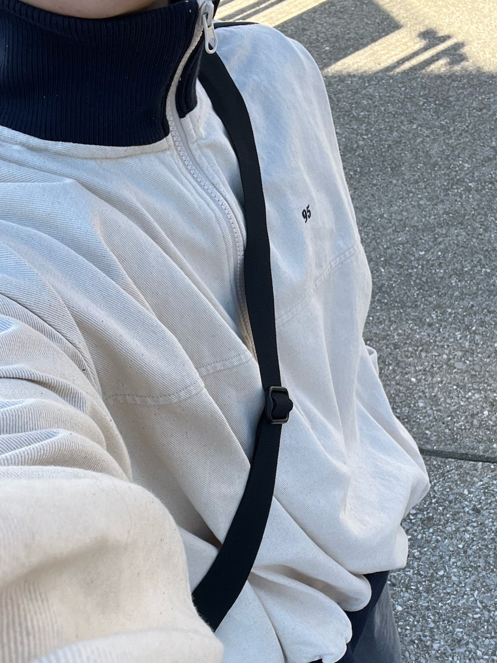 グレー系のデニムパンツ、ブラック系のスニーカー、ベージュ系のトップスを着用したメンズの冬コーディネートの3枚目の写真