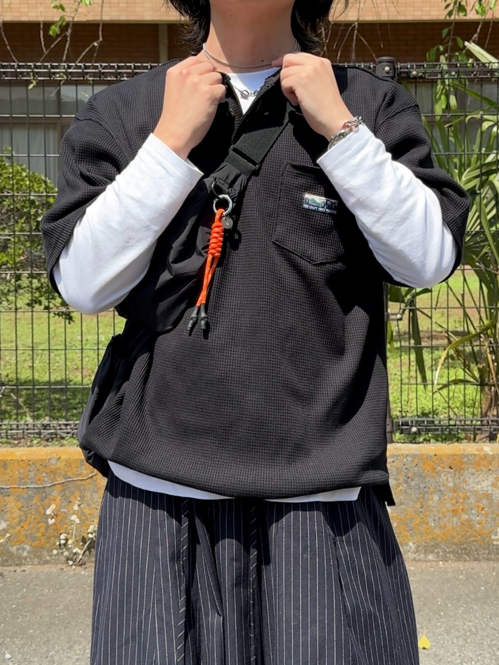 ブラック系のTシャツ/カットソー、グレー系のスラックス、ブラック系のスニーカーを着用したメンズの春コーディネートの2枚目の写真