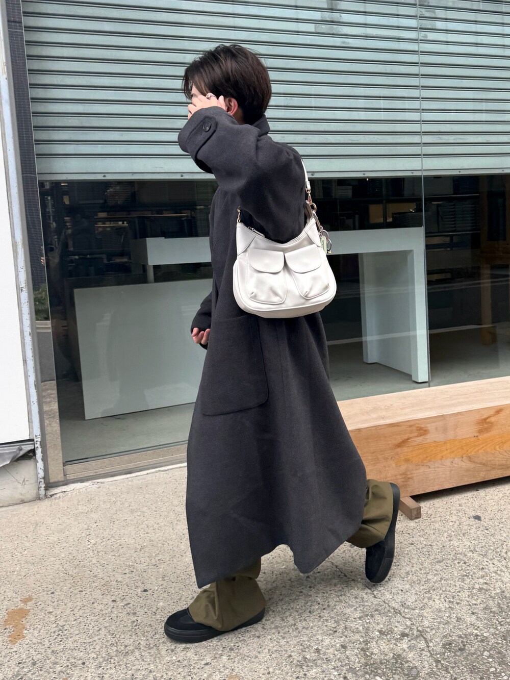 ホワイト系のショルダーバッグ、グレー系のステンカラーコート、ベージュ系のスウェットを着用したメンズの冬コーディネートの2枚目の写真
