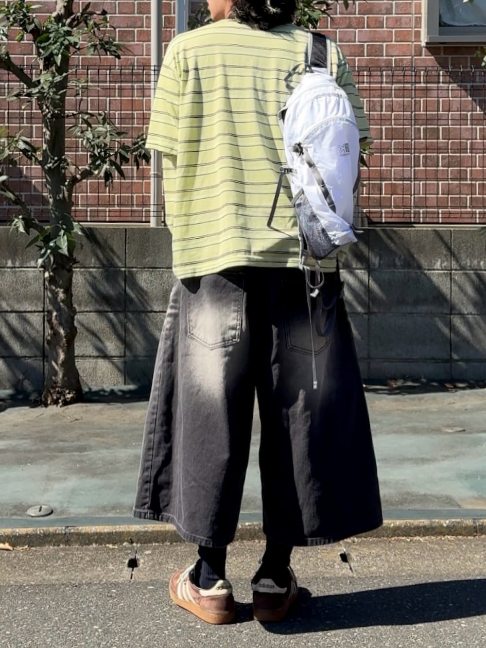 ベージュ系のデニムパンツ、イエロー系のTシャツ/カットソー、ホワイト系のバックパック/リュックを着用したメンズの秋コーディネートの2枚目の写真