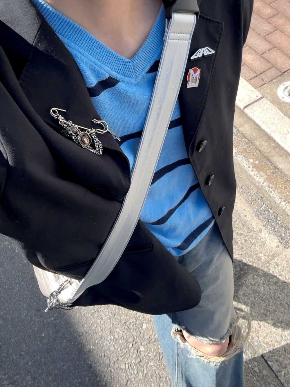 ブラック系のスニーカー、ブルー系のデニムパンツ、シルバー系のバッグを着用したメンズの春コーディネートの4枚目の写真