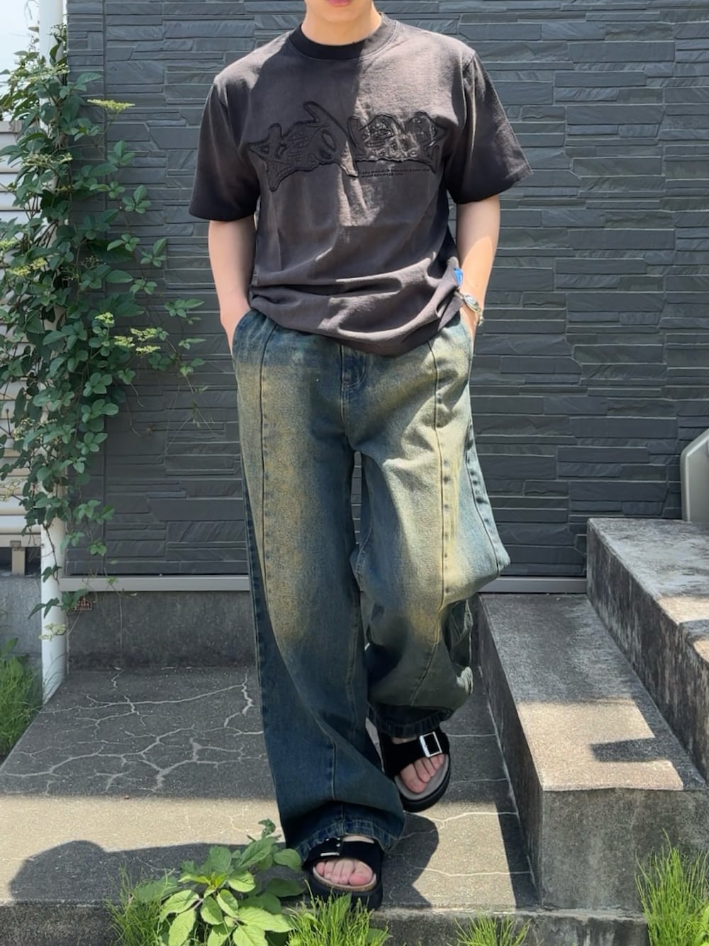 ブラック系のTシャツ/カットソー、ブルー系のデニムパンツ、ホワイト系のサンダルを着用したメンズの夏コーディネートの3枚目の写真