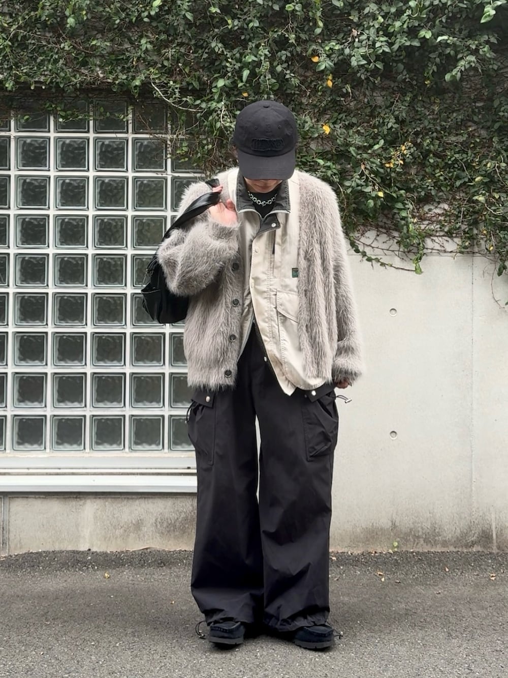 ブラック系のショルダーバッグ、ブラック系のカーゴパンツ、ホワイト系のベストを着用したメンズの秋コーディネートの2枚目の写真