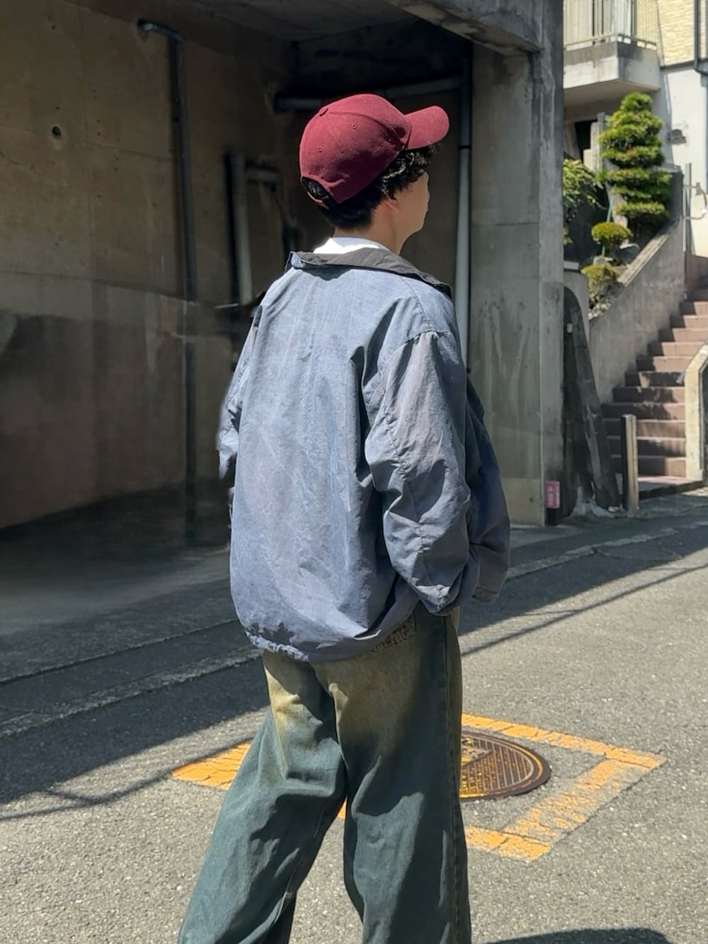 ブルー系のデニムパンツ、ブラック系のスニーカー、ベージュ系のブルゾンを着用したメンズの秋コーディネートの2枚目の写真