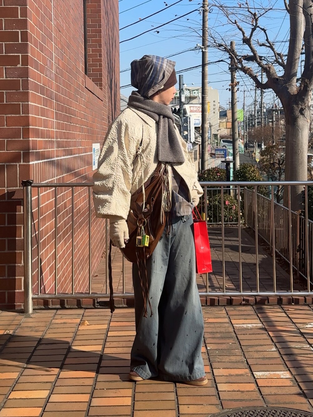 ブラック系のデニムパンツ、ブラウン系のスニーカー、ブラウン系のショルダーバッグを着用したメンズの冬コーディネートの2枚目の写真