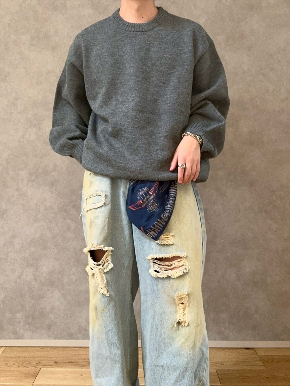 ブラック系のステンカラーコート、グレー系のニット/セーター、ブルー系のデニムパンツを着用したメンズの冬コーディネートの3枚目の写真